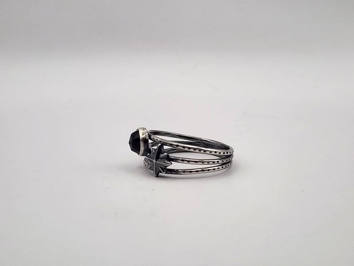 A sterling silver ring with a round amethyst and a star accent on a three band ring with texture, photographed on a plain light background.