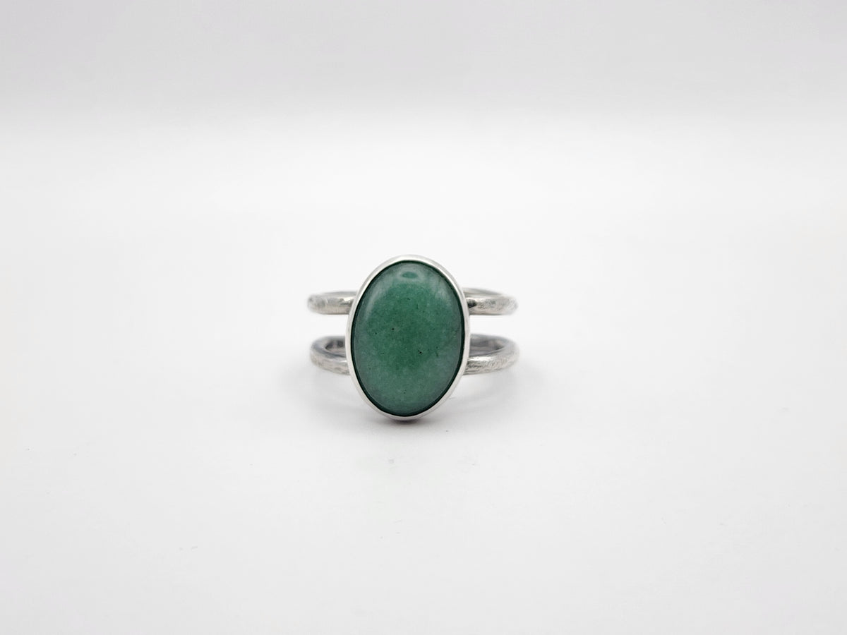 A sterling silver ring with a large green oval stone and split ring band, photographed on a white background. 
