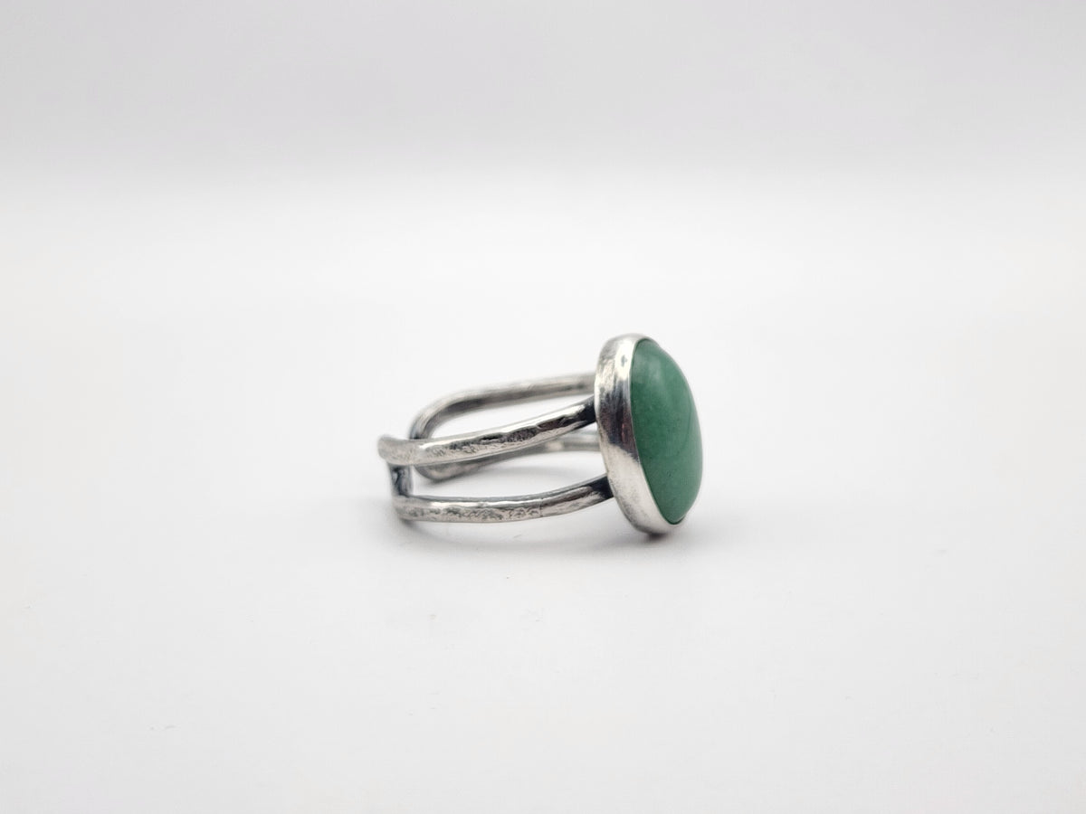 A side view of a sterling silver ring with a large green oval stone and split ring band, photographed on a white background. 