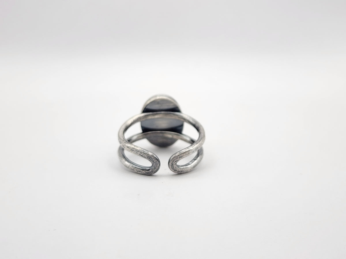 A sterling silver ring photographed from the back with an open ring band in the back, photographed on a white background.