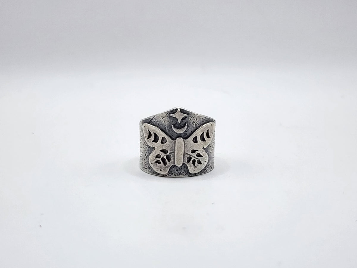 A sterling silver butterfly ring with a crescent moon and star at the top with a textured, oxidized finish, photographed on a plain white background.