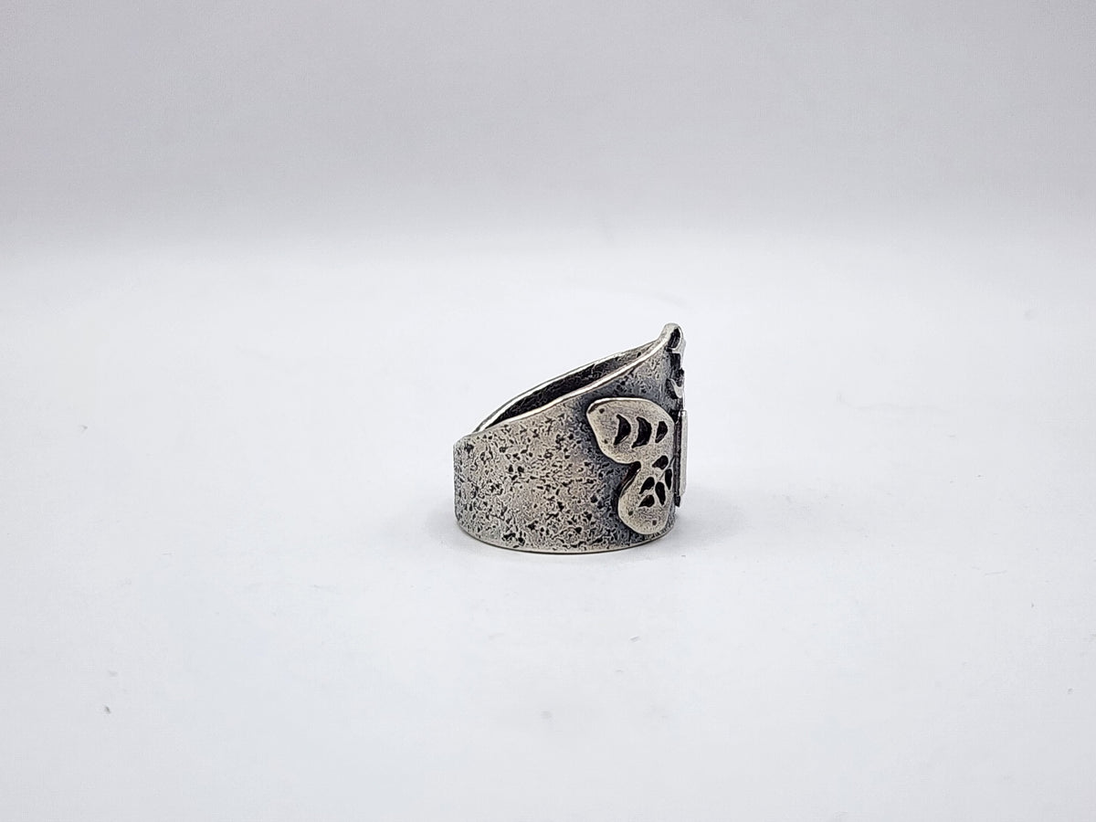 A side view of a sterling silver butterfly ring with a crescent moon and star at the top with a textured, oxidized finish, photographed on a plain white background.