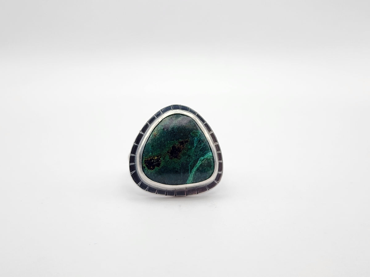 Sterling silver ring with large triangular green stone and border with lines, on a white background.