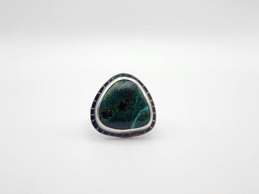 Sterling silver ring with large triangular green stone and border with lines, on a white background.