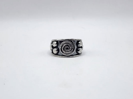 A sterling silver ring with a central spiral design and small circular/dot details on the sides, photographed on a plain white background.