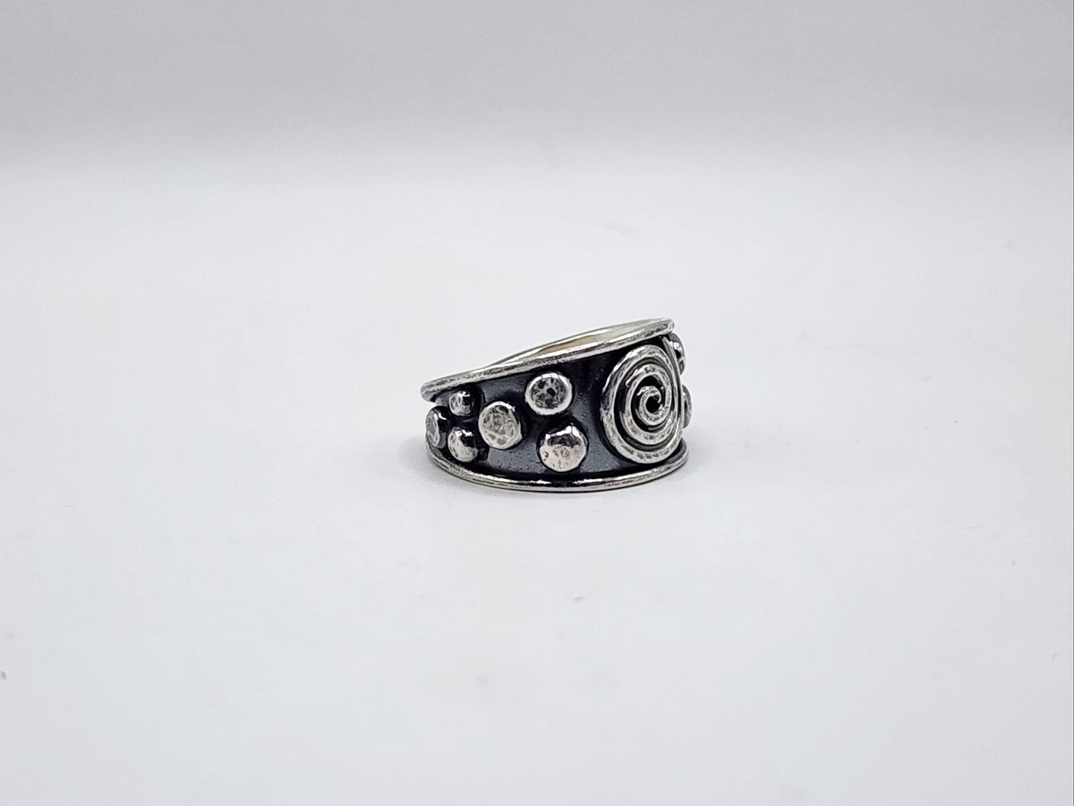 A sterling silver ring with a spiral design and small raised circular/dot details, photographed on a white background.