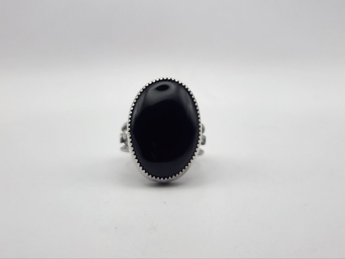 A sterling silver ring featuring a large, oval-shaped black onyx cabochon stone, photographed against a neutral light gray background.
