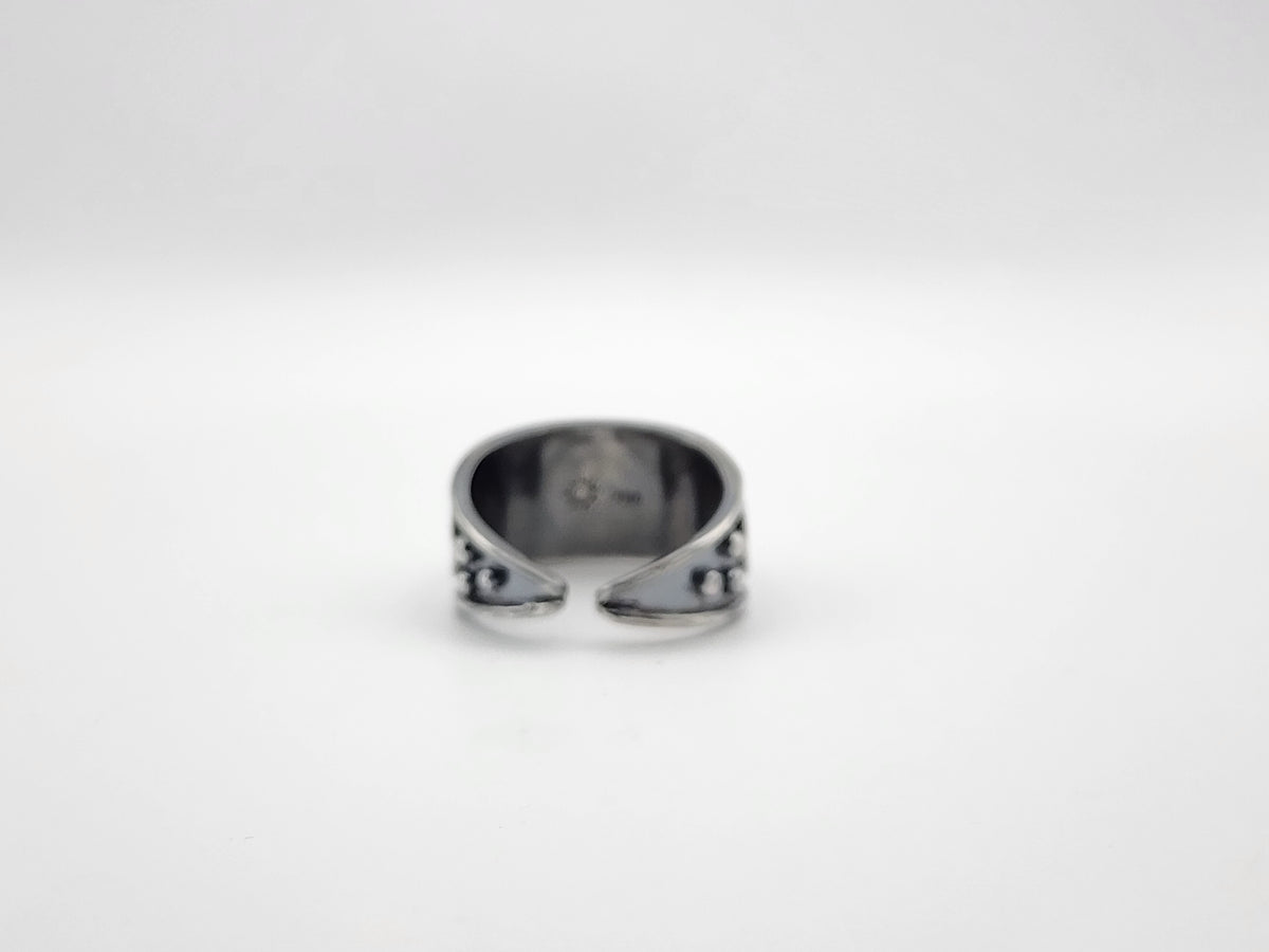 A sterling silver open band ring with small decorative details on the sides, photographed from the back of the ring against a plain light gray background.