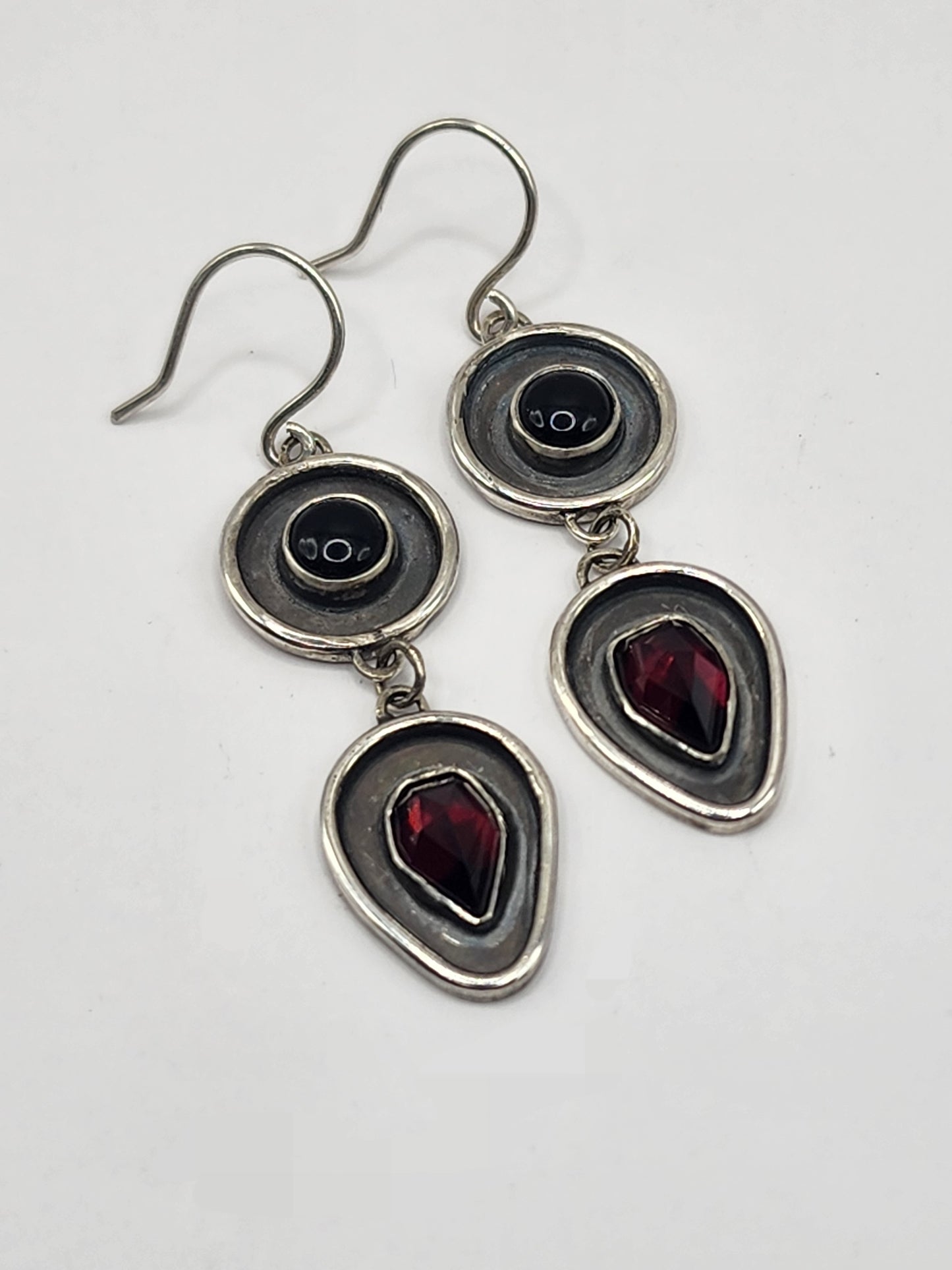 Silver earrings with black and red gemstones on a white background