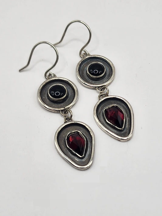 Silver earrings with black and red gemstones on a white background