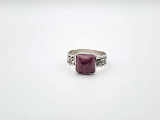 Silver ring with a purple stone on a white background, front view of ring