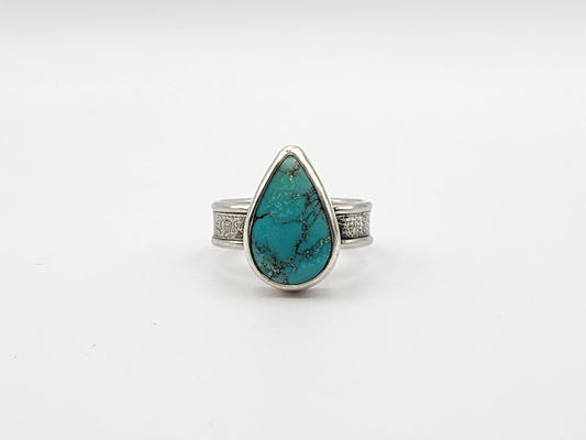 Front view of turquoise ring with textured silver band on a white background