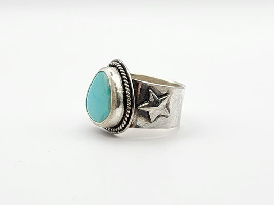 Side view of silver ring with turquoise stone and star design on a white background
