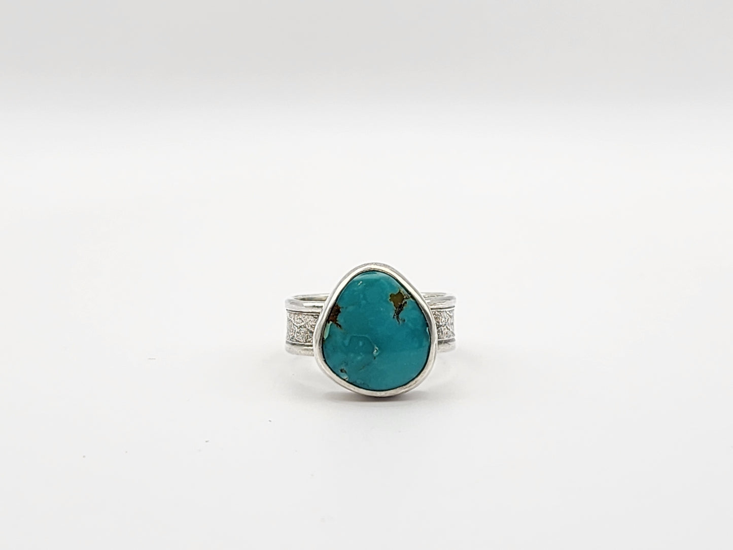 Ring with a turquoise stone and silver band on a white background