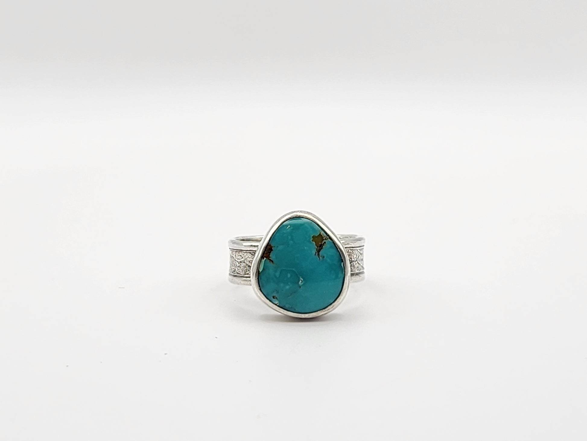 Ring with a turquoise stone and silver band on a white background